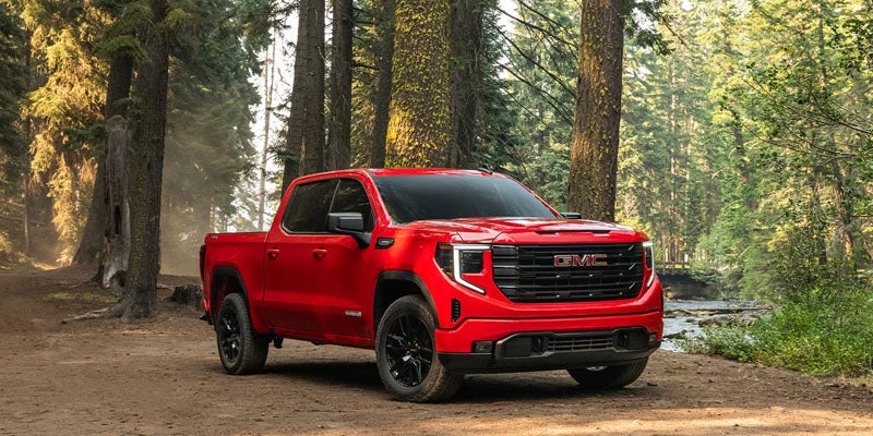2026 GMC Sierra 1500 driving on rugged forest trail showcasing off-road.